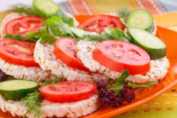 Puffed rice crackers sandwiches with vegetables on plate.