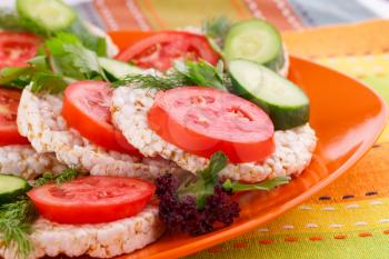 Puffed rice crackers sandwiches with vegetables on plate.