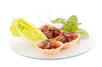 Anchovies in pastries, lettuce and basil on plate isolated on white background.
