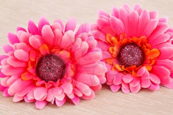 Pink fabric daisies on beige cloth background.