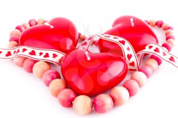 Red heart candles, wooden necklace and ribbon isolated on white background.