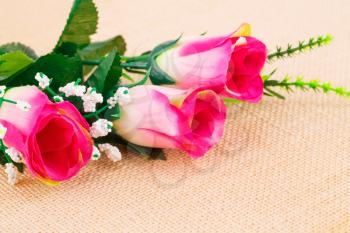 Pink fabric roses on beige cloth background.