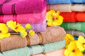 Colorful towels stacks with flowers closeup picture.