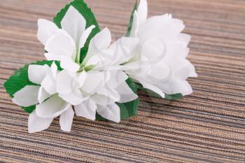 White artificial flowers on cloth background, closeup picture.