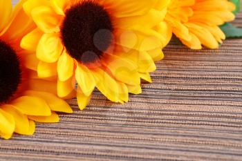 Yellow fabric daisies on striped cloth background.