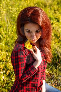 Young pretty woman with yellow daisy flowers in field.