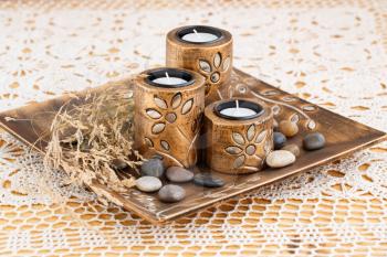 Three brown ancient style candle nests in plate on cloth background.
