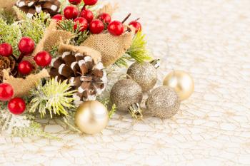 Christmas decoration with burlap ribbon, holly berries , balls and cones on the golden net.