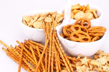 Different salted crackers in bowl on white background.