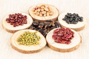 The collection of different beans on the wooden round boards.