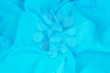 Crumpled blue crepe paper texture as a background.