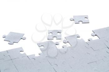 Unfinished jigsaw puzzle pieces on white background.