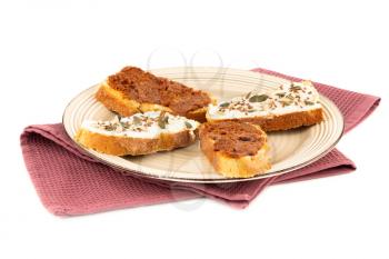 Sandwiches with cheese and sundried tomatoes on beige  plate on towel isolated on white background.