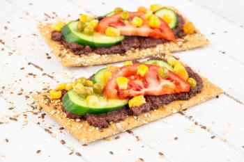 Sandwiches with olive paste, tomato, cucumber, corn and pea  on gray wooden background.