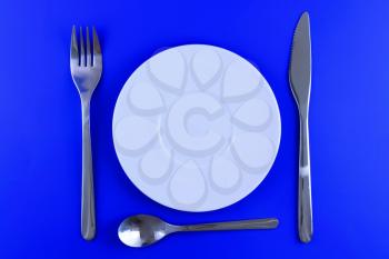Table serving-knife,plate,fork on  various colour background.