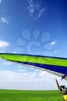 Motorized hang glider over green grass, ready to fly.