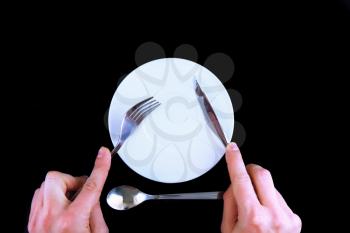 Table serving-knife, fork in hands on black background.