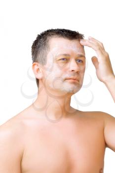 A young man puts on face cream mask . Isolated over white