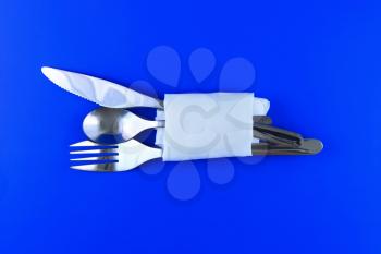 Table serving-knife,plate,fork and silk napkin  on  blue colour background.