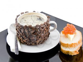 Cup of coffee with cream, red caviar on bread. Isolated over white