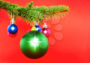 Christmas decoration-colour balls on fir branches on red background .