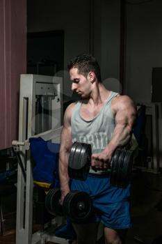 bodybuilder doing heavy weight exercise for shoulder white dumbbell