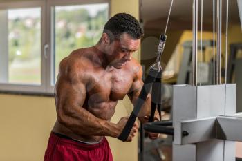 bodybuilder doing heavy weight exercise for triceps with cable