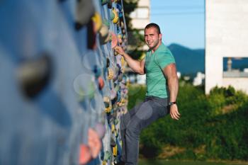 young man climbing wall rock outdoors