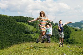mother and her kids jumping in meadow