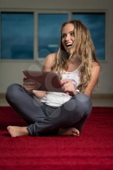 Happy Woman Using iPad While Siting On Carpet