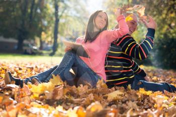 Young Couple With Headphones And Throwing Fall Leaves