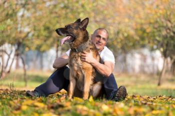 Adult Man Sitting Outdoors With His German Shepherd
