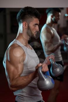 Men In Gym Exercising With Kettle Bell