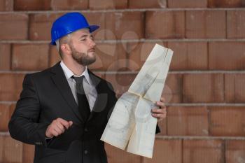 Portrait Of Construction Master With Blue Helmet And Blueprint In Hands