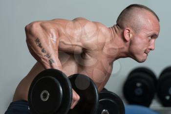 Healthy Man Doing Back Exercises In The Gym With Dumbbell