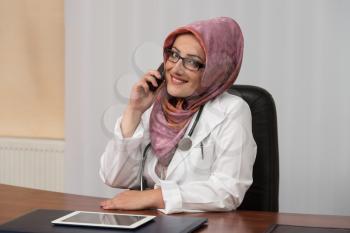 Muslim Doctor Working At Her Computer While Talking On The Phone