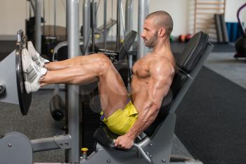 Attractive Young Man Doing Leg Press On Machine In Gym