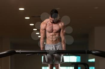 Young Bodybuilder Doing Dips on Bar Exercising Triceps On Machine In Gym
