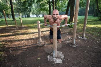 Young Athlete Working Out Triceps In An Outdoor Gym - Doing Street Workout Exercises
