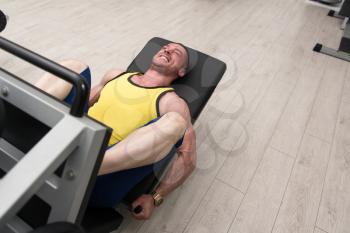 Young Man Using The Leg Press Machine At A Health Club In Gym