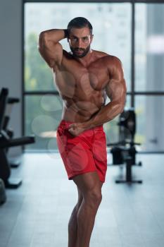 Portrait Of A Young Physically Fit Latin Man Performing Side Chest Pose - Muscular Athletic Bodybuilder Fitness Model Posing After Exercises