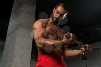 Latin Muscular Fitness Bodybuilder Doing Heavy Weight Exercise For Biceps On Machine With Cable In The Gym