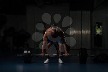 Muscular Hispanic Man Doing Heavy Weight Exercise For Back With Barbell In Modern Gym