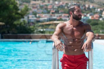 Portrait Of A Happy Attractive Muscular Man Posing In Swimming Pool