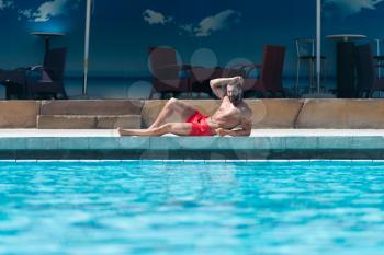 Portrait Of A Happy Attractive Muscular Man Resting At Swimming Pool