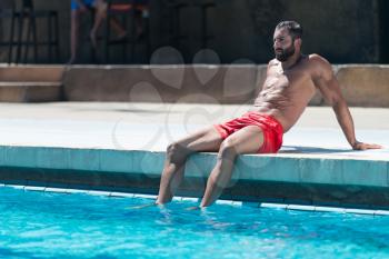 Portrait Of A Happy Attractive Muscular Man Resting At Swimming Pool