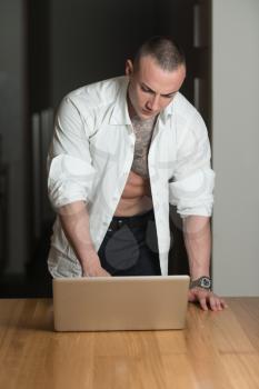 Man Working From Home on a Laptop Computer Standing at a Desk Surfing the Internet