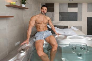 Wellness Spa - Man Relaxing in Hot Tub Whirlpool Jacuzzi Indoors at Luxury Resort Spa Retreat - Handsome Young Male Model Relaxed Resting in Water Near Pool on Travel Vacation Holiday