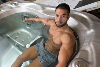 Wellness Spa - Man Relaxing in Hot Tub Whirlpool Jacuzzi Indoors at Luxury Resort Spa Retreat - Handsome Young Male Model Relaxed Resting in Water Near Pool on Travel Vacation Holiday