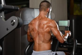 Young Muscular Fitness Bodybuilder Doing Heavy Weight Exercise For Back On Machine In The Gym